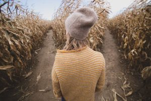 woman walking through fall corn maze